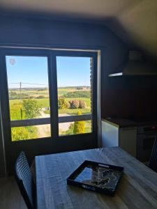 a room with a table and two windows with a view at A l'orée du Bois in Landelies