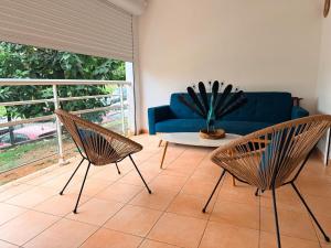 a living room with a blue couch and two chairs at L'ile au Paon in Les Abymes