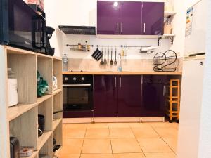a kitchen with purple cabinets and a tile floor at L'ile au Paon in Les Abymes