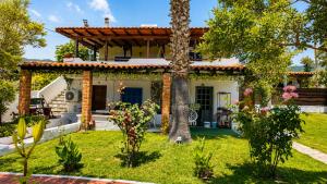 a house with a palm tree in the yard at Casa de Palma in Asprovalta