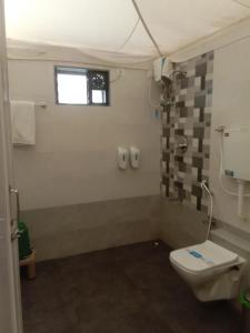 a bathroom with a toilet and a window at Krishna's den- a cottage retreat a Gaudham Periyar Farmstay in Jambhulpāda +22 photos
