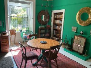 a green room with a wooden table and chairs at Mansefield Rooms in Lockerbie