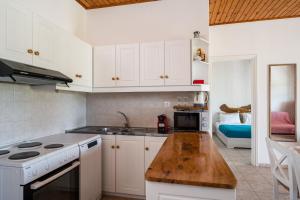 a kitchen with white cabinets and a wooden counter top at Serenity Apartments, Next to the Beach in Agios Georgios +13 photos
