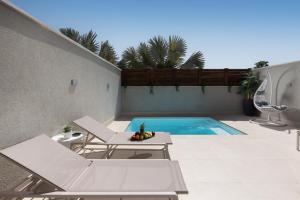 a swimming pool with two lounge chairs and a table at Coral suites Boutique in Eilat