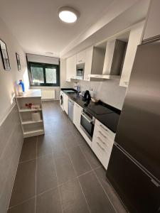 a kitchen with white cabinets and a black refrigerator at Playa América 2C by YBH in Nigrán