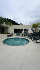 a pool with tables and chairs in a patio at Mar e Natureza 2 quartos 6 Pessoas Lazer in Bertioga