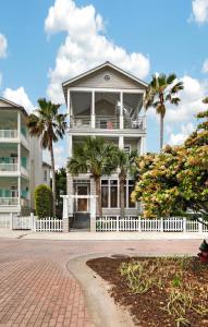 a house with a white fence and palm trees at Emil Cottage in Saint Simons Island