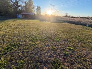 a field with the sun setting in the distance at Przystań Lubikowo in Lubikowo