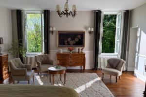 a living room with chairs and a table and two windows at La Maison 1680 in Couches