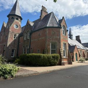 a large brick building with a clock tower at Old Schoolhouse Coleraine in Coleraine