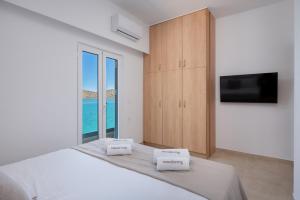 a white bedroom with a large bed with a large window at Blue Horizon Elounda in Elounda