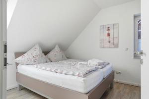 a bed with white sheets and pillows in a room at Nordseeperle in Greetsiel