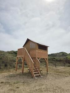 a wooden play house with a staircase in a field at Camping de Mer - Onlycamp in Cucq +2 photos