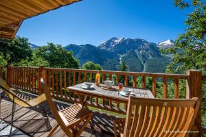 a table and chairs on a deck with a view of mountains at Chalet la Forestière in Orcières