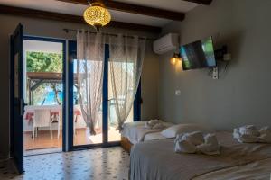 two beds in a room with a view of a patio at Apágkio Filoxenia in Archangelos