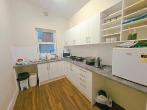 a kitchen with white cabinets and a wooden floor at Eden - Franklin 6 in Adelaide +8 photos