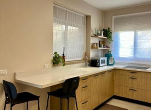 a kitchen with a sink and a counter with chairs at זוג ידיים - סוויטה עם בריכה פרטית, סאונה וג'קוזי in H̱osen