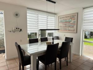 a dining room with a white table and black chairs at Ooghduyne 89 in Julianadorp