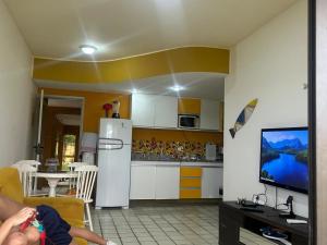 a kitchen with a white refrigerator and a tv at GAVOA Beach FLAT in Água Boa