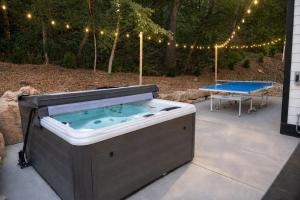 a jacuzzi tub sitting on a patio next to a table at Cliffside Modern Villa. Secluded and accessible. in Asheville