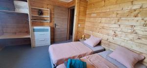 a bedroom with two beds and a wooden wall at La Maison En Bois in Figeac +8 photos