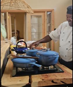 a chef is preparing blue pots on a stove at TheCabinsNanyuki in Nanyuki