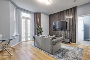 a living room with a couch and a tv on a wall at Reeha's Hotel Apartments in Southend-on-Sea