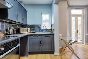 a kitchen with blue cabinets and a glass table at Reeha's Hotel Apartments in Southend-on-Sea
