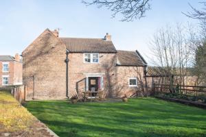 ein Backsteinhaus mit einem Rasenvorplatz in der Unterkunft Carlton Towers Estate - Stapleton Rooms & Parkgate Cottages in Carlton