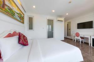 a white bedroom with a large bed and a tv at Michael Hotel in Nha Trang