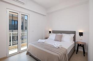 a white bedroom with a bed and a balcony at Blue Horizon Elounda in Elounda +22 photos