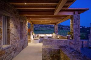 an outdoor living room with a stone wall and a wooden ceiling at Mystic Horizon in Mikonos