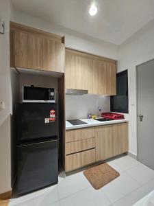 a kitchen with a black refrigerator and wooden cabinets at Maru Maya Bay Guest House in Banting