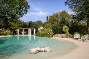 a swimming pool with a rock in the water at Puntebianche Resort in Ceglie Messapica