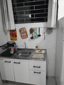 a kitchen with white cabinets and a sink at EM CASA in Palhoça +29 photos