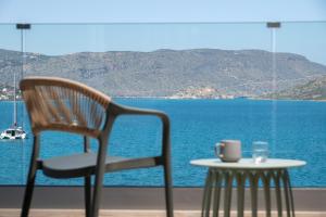 a chair and a table with a cup and a view of the ocean at Blue Horizon Elounda in Elounda