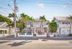 a white building with palm trees on a street at NIGHTCAP @ Speakeasy Inn Key West! in Key West +5 photos
