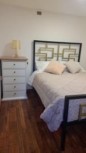 a bedroom with a bed and a dresser with a lamp at Central Zenteno en Punta Arenas in Punta Arenas
