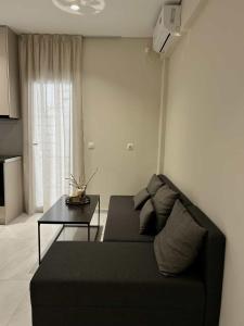 a living room with a black couch and a table at Kostas apartaments in Korinthos