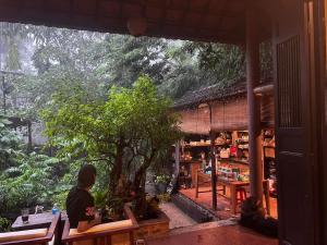 a man sitting at a table in front of a tree at mehome Hidden Garden Homestay in Cư Chinh