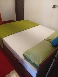 a bed with green and white sheets on it at Ella Top Sky in Bandarawela