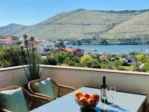 a table with a bottle of wine and a bowl of fruit at Sea View Apartments in Grebaštica