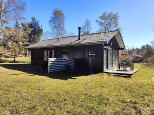 a small black house with a porch on a field at 1617-Aakirkeby-Poserekrogen-27 in Vester Sømarken