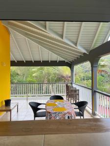 a patio with a table and chairs on a porch at Le coin des plaisir in Deshaies +6 photos