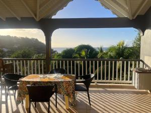 a porch with a table and chairs on a balcony at Le coin des plaisir in Deshaies