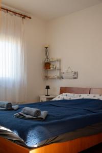a bedroom with a bed with blue sheets and a window at Apartman Jedro in Vukovar