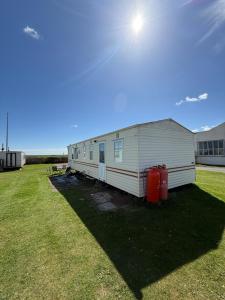 a mobile home in a field with two trash cans at Holiday Home Arbroath in Arbroath
