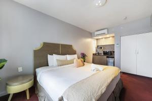 a bedroom with a large white bed and a yellow chair at Alamo Hotel in Miami Beach
