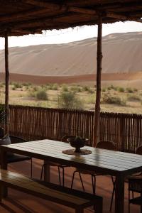 a table and chairs on a porch with a view of the desert at Liwa Nights ليالي ليوا in Liwa