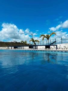 a swimming pool with blue water and palm trees at Domaine Residence in Gravatá